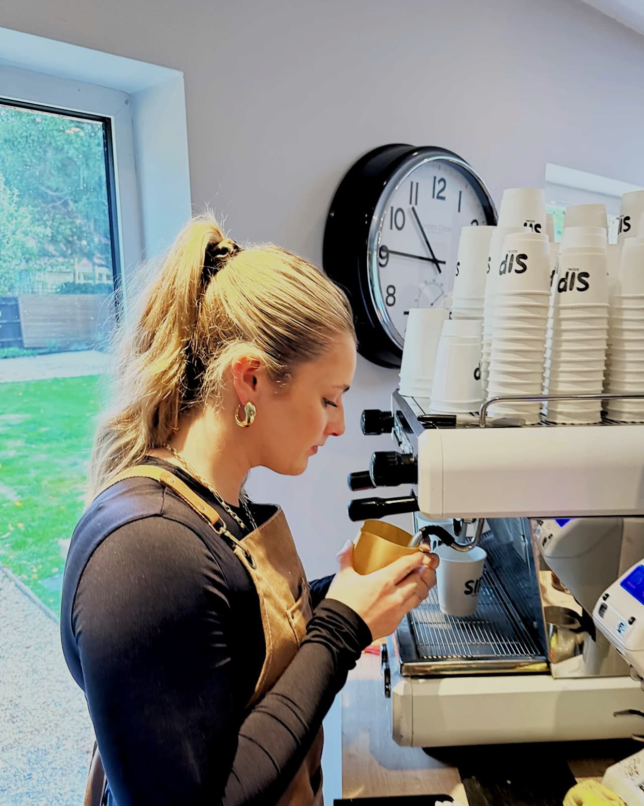A Sip Social barista steaming milk at the espresso machine